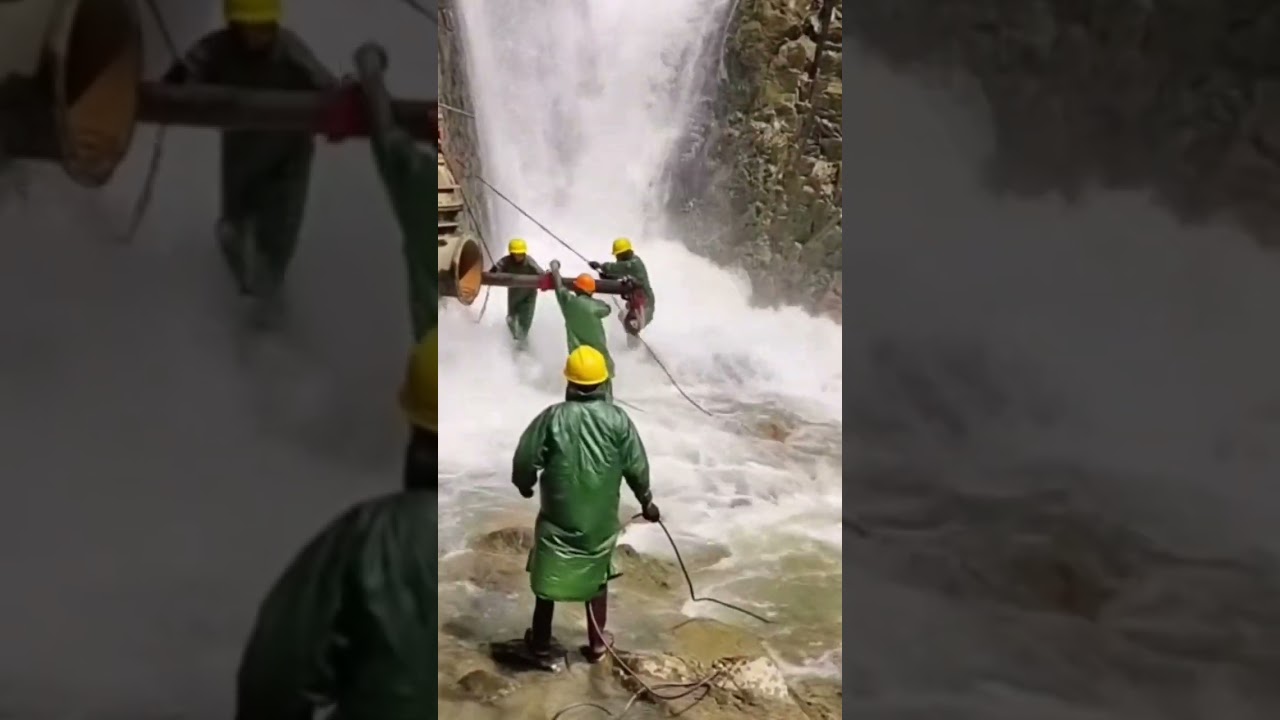Hard workers fixing pipe under waterfall