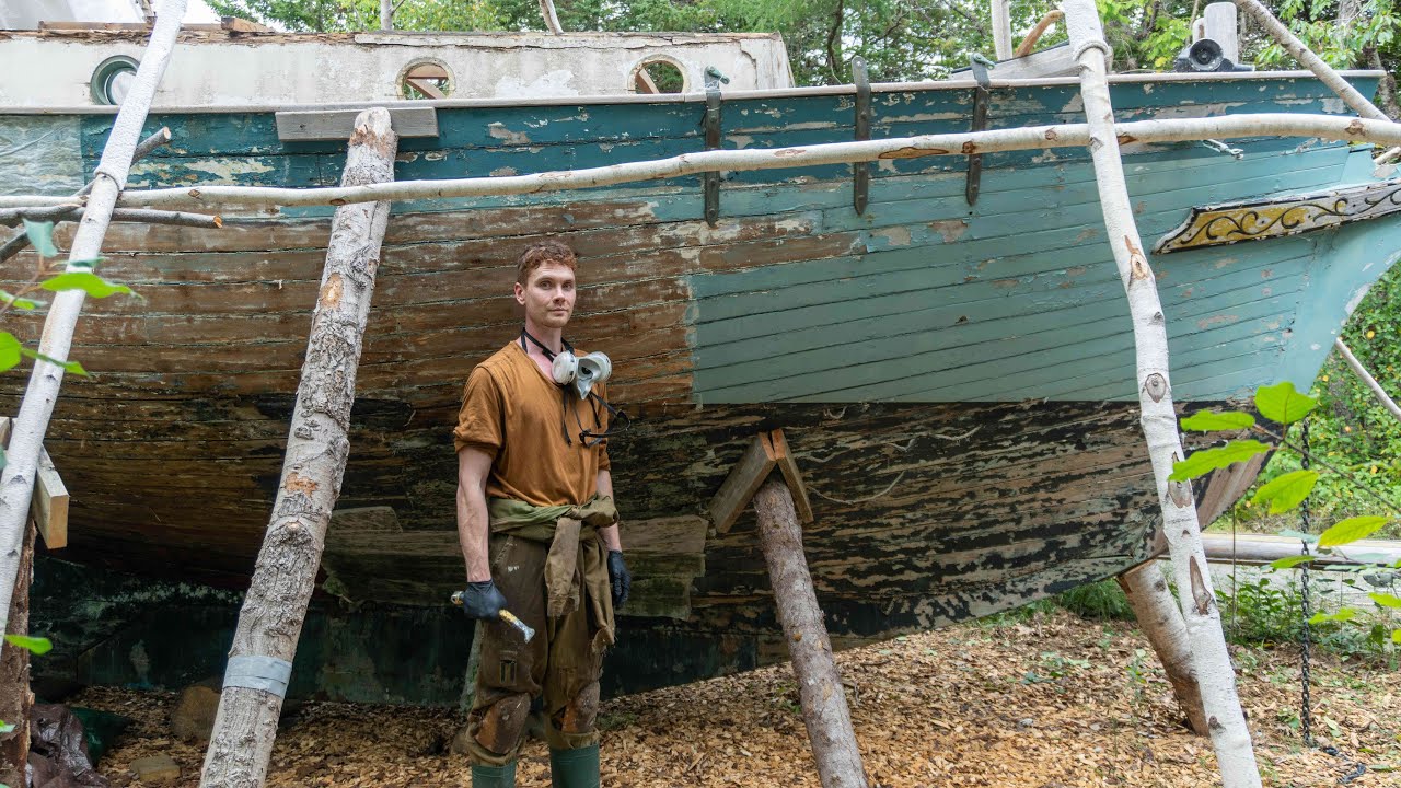 Removing decades of paint from old wooden sailboat in the forest - no. 16