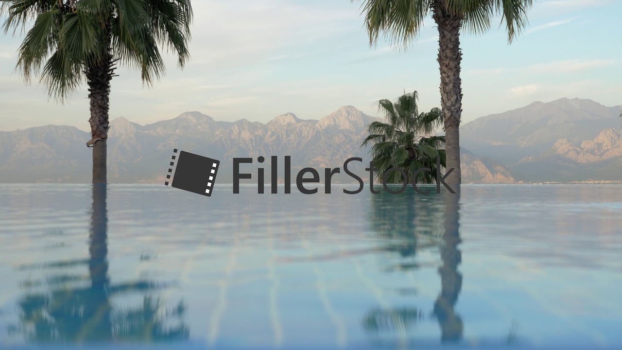 Outdoor swimming pool with palms and mountains scene