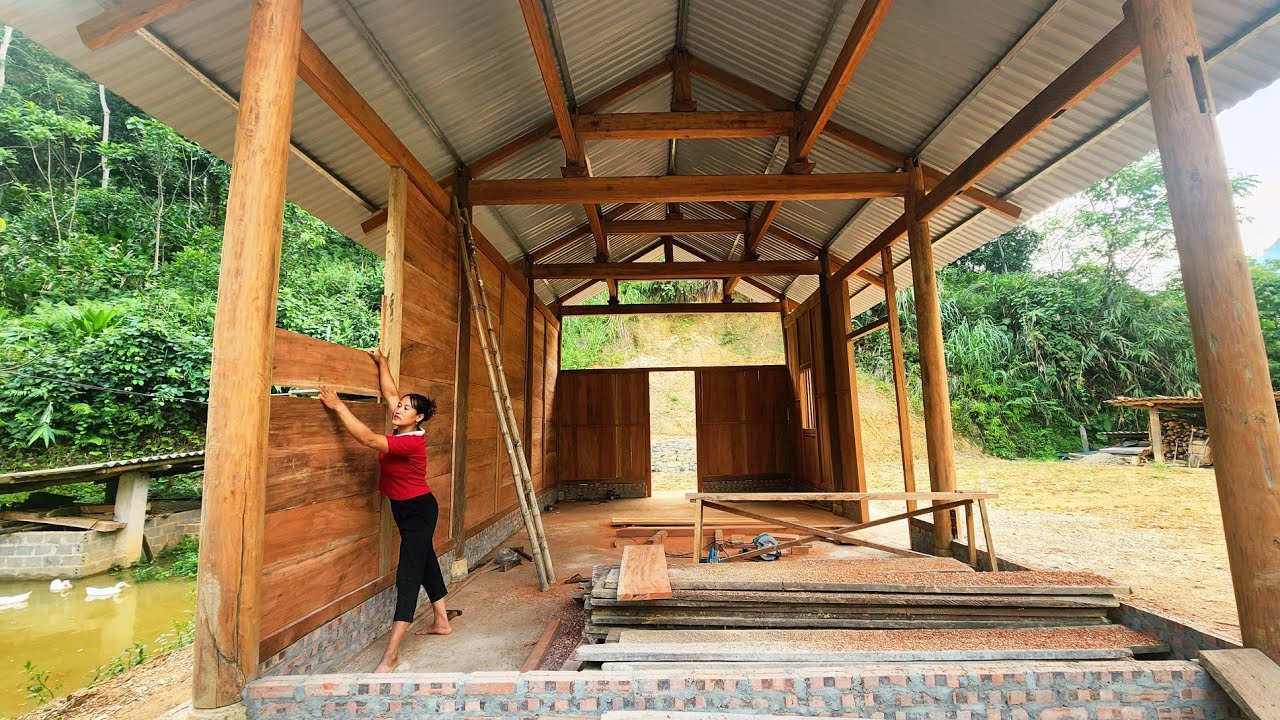 The girl has erected the wooden walls; the construction is about 80% complete.
