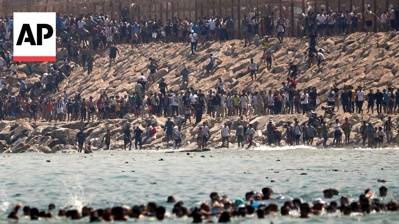Thousands of migrants swim around the border from Morocco into Ceuta, Spain
