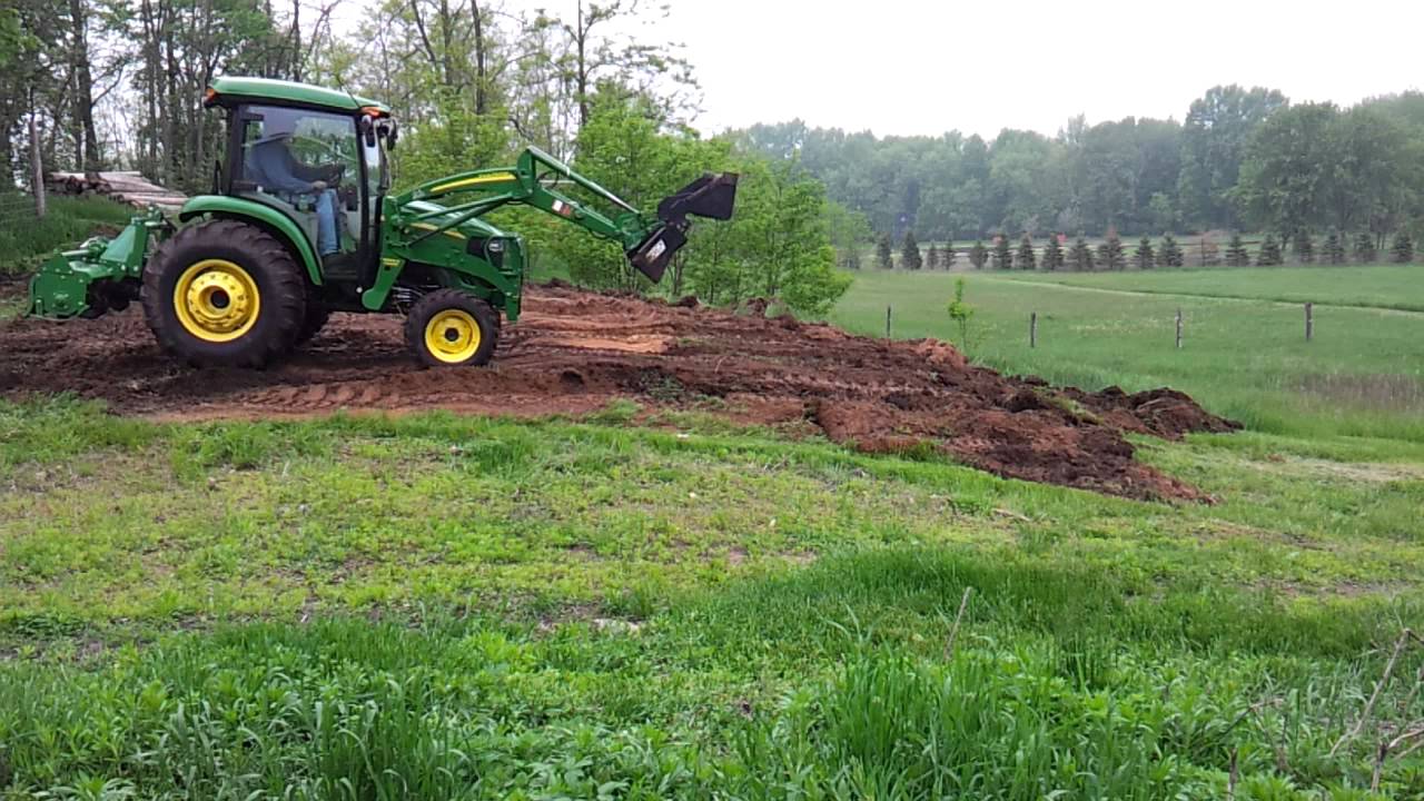 John deere 4720 bulldozing down hill on farm