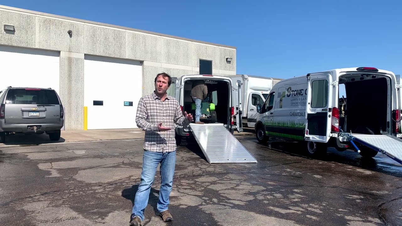 Ford Transit vans demonstrating two loading ramps with a Turfco T3100 Spreader Sprayer machine.