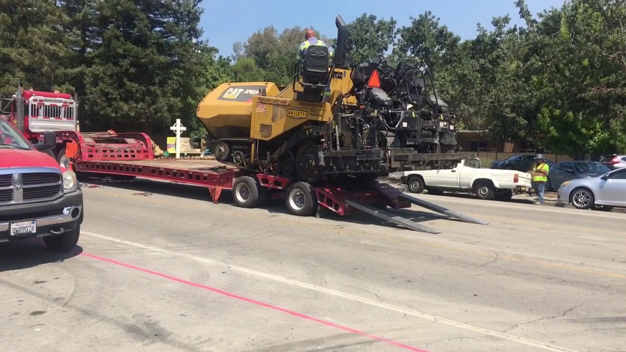 Loading a cat paver over the back of a transport trailer