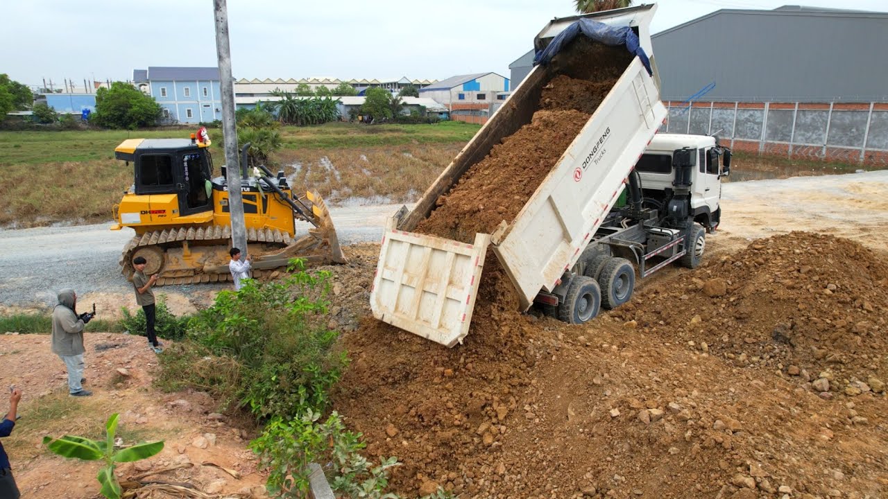 Continue work ! By dump truck wheel 10 unloading stone landfill flooded with bulldozer pushing stone