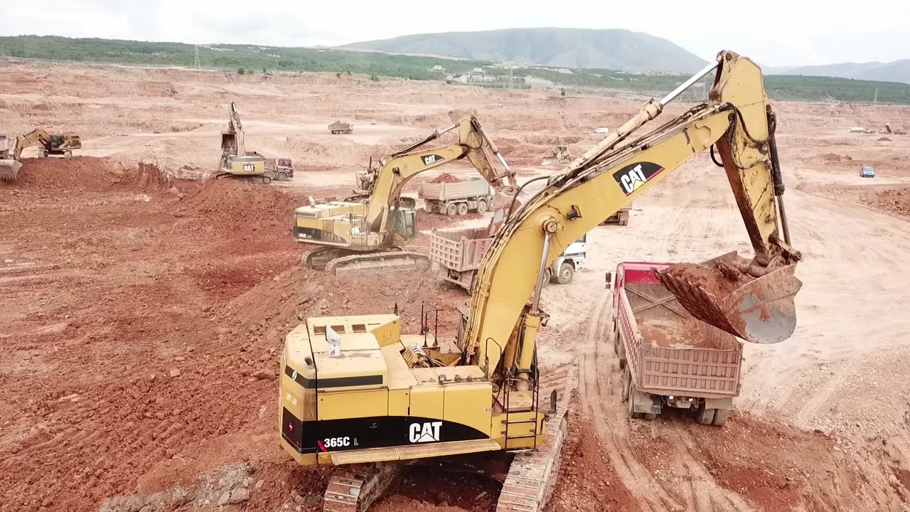 Five Caterpillar Excavators And A Fleet Of 4 Axle Trucks Working On A Huge Mining Area - Aerial View