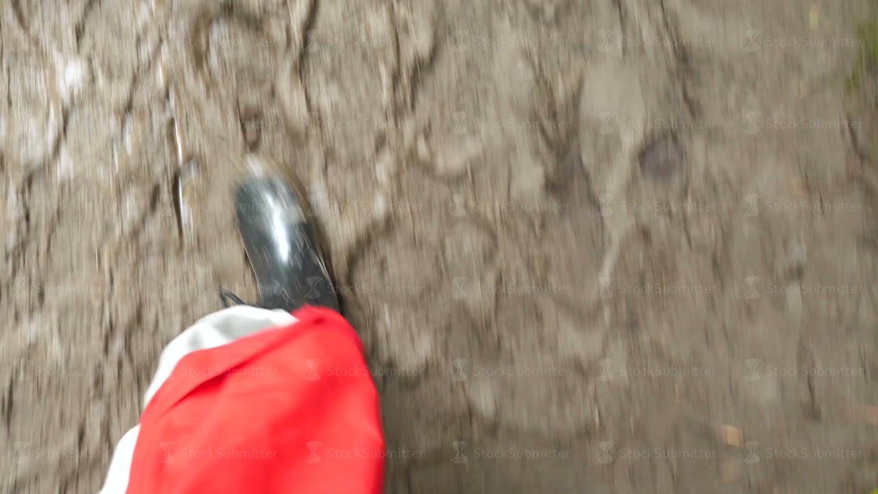 Man steps in muddy puddles in rubber boots top view. Legs in the mud puddle in a shoe full of holes