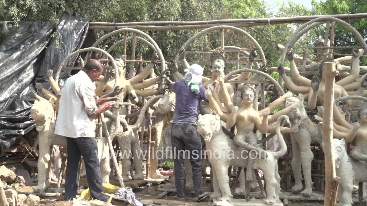 Two skilled craftsmen carefully shape a Durga idol in an open space at Vasant Vihar