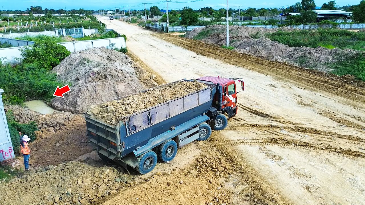 Nice skill bulldozer leveling road with dump trucks working hard