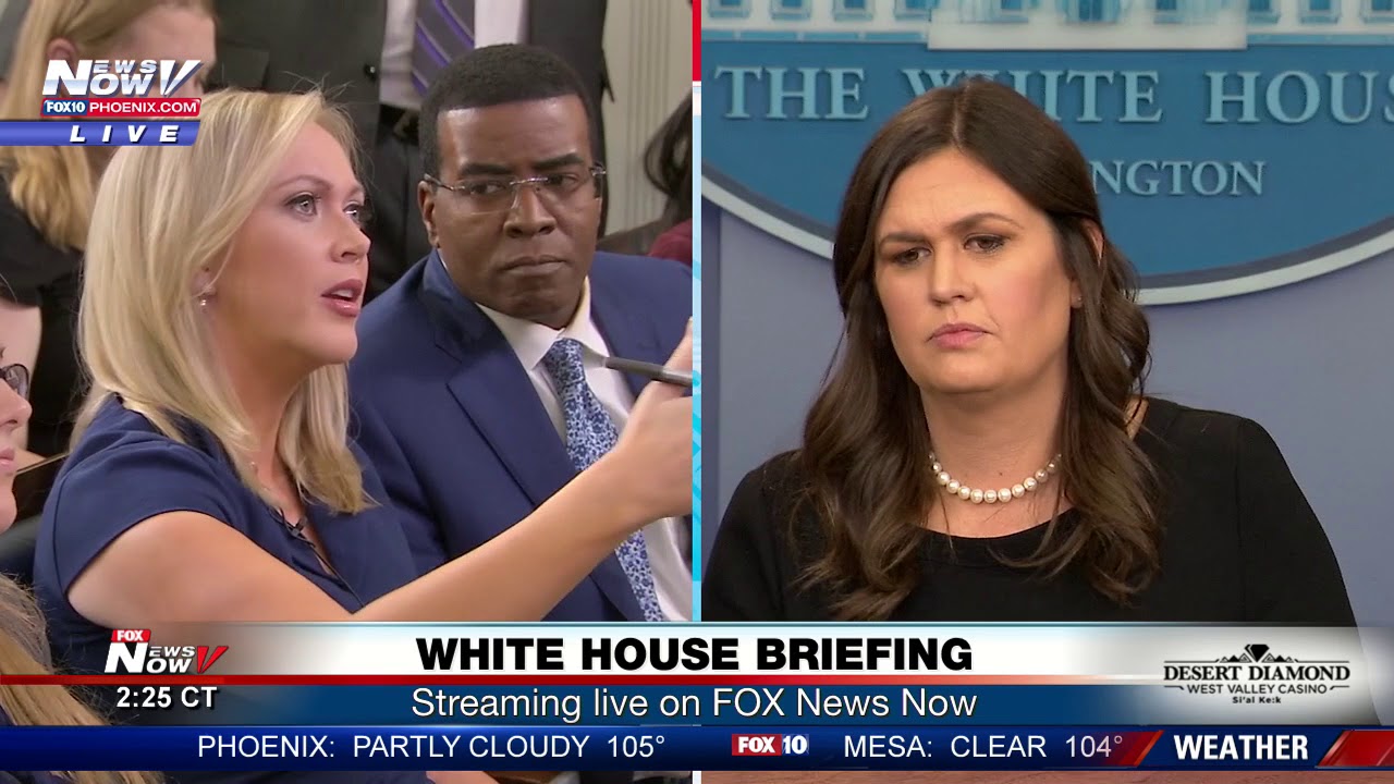 Between reporters, Sarah Sanders at White House press briefing (FNN)