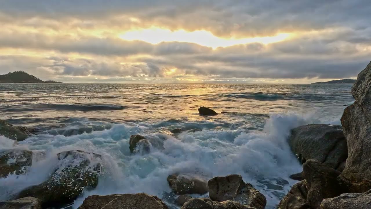 Ocean Waves Crashing on Rocks with Dark Cloudy Skies & a Bright Sun trying to set, Carmel, CA