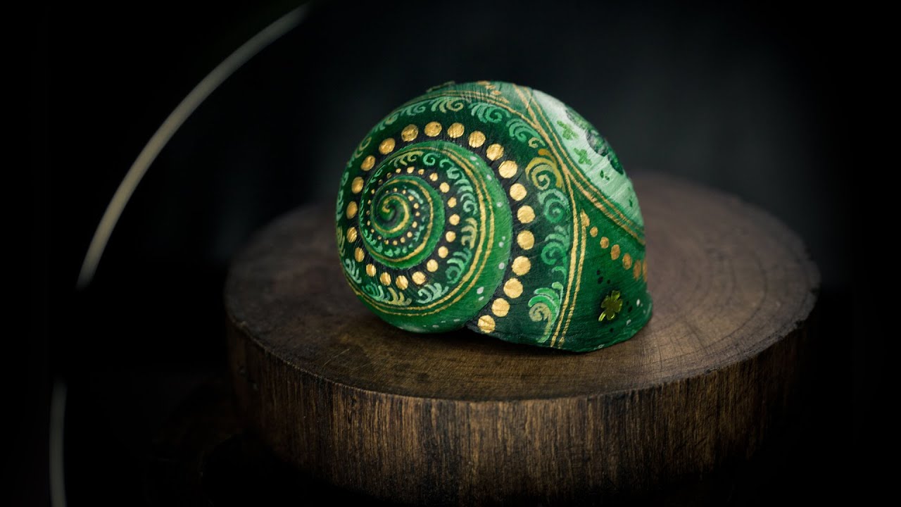 Painting a green cloverleaf on a snail shell