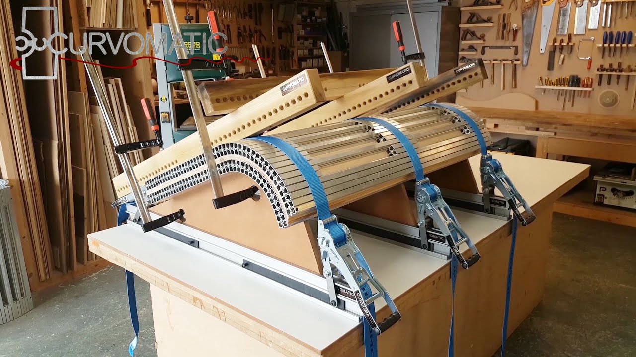 Laminating a curved door panel with a flat section.