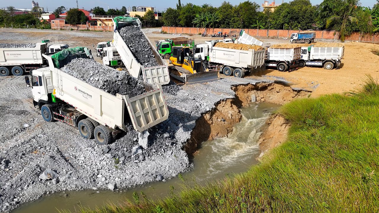 Attention! The giant lake landfill uses bulldozer to move rocks and dump trucks to transport them