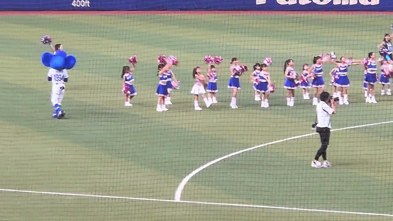 小さなチアガールの落としたポンポンゴミを拾う先生
