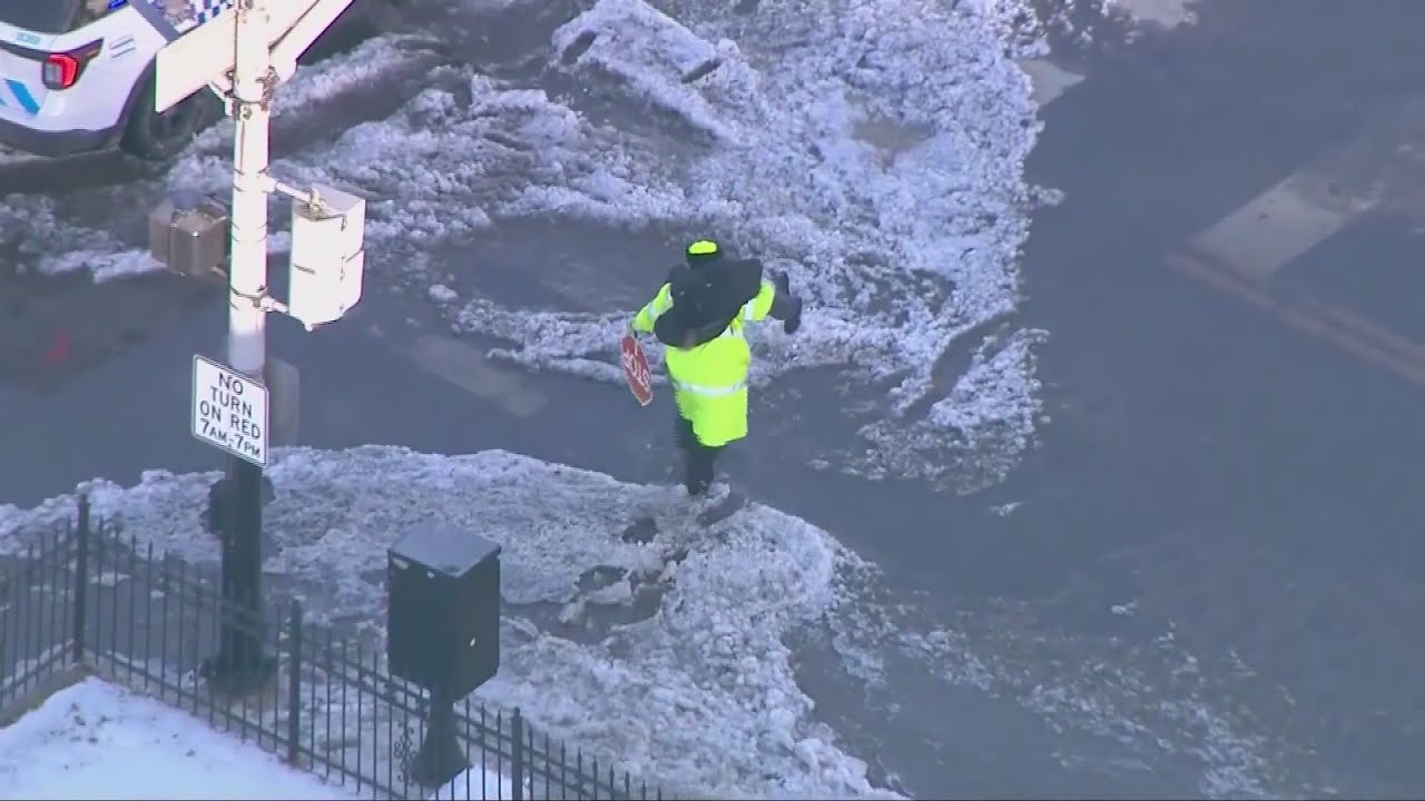 Crossing guard carries child across flooded Chicago street
